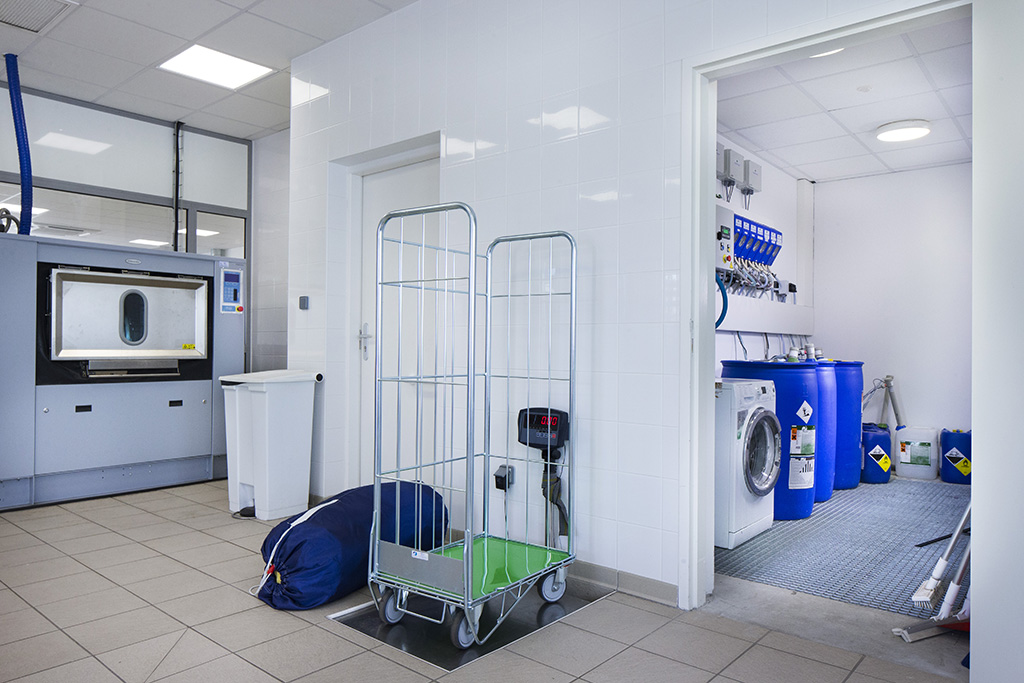 Transfert et manipulation de charges lourdes en blanchisserie ESAT, balance. Activité blanchisserie dans un ESAT -Charge physique de travail (manutention manuelle et levage)-Transfert et manipulations de charges lourdes